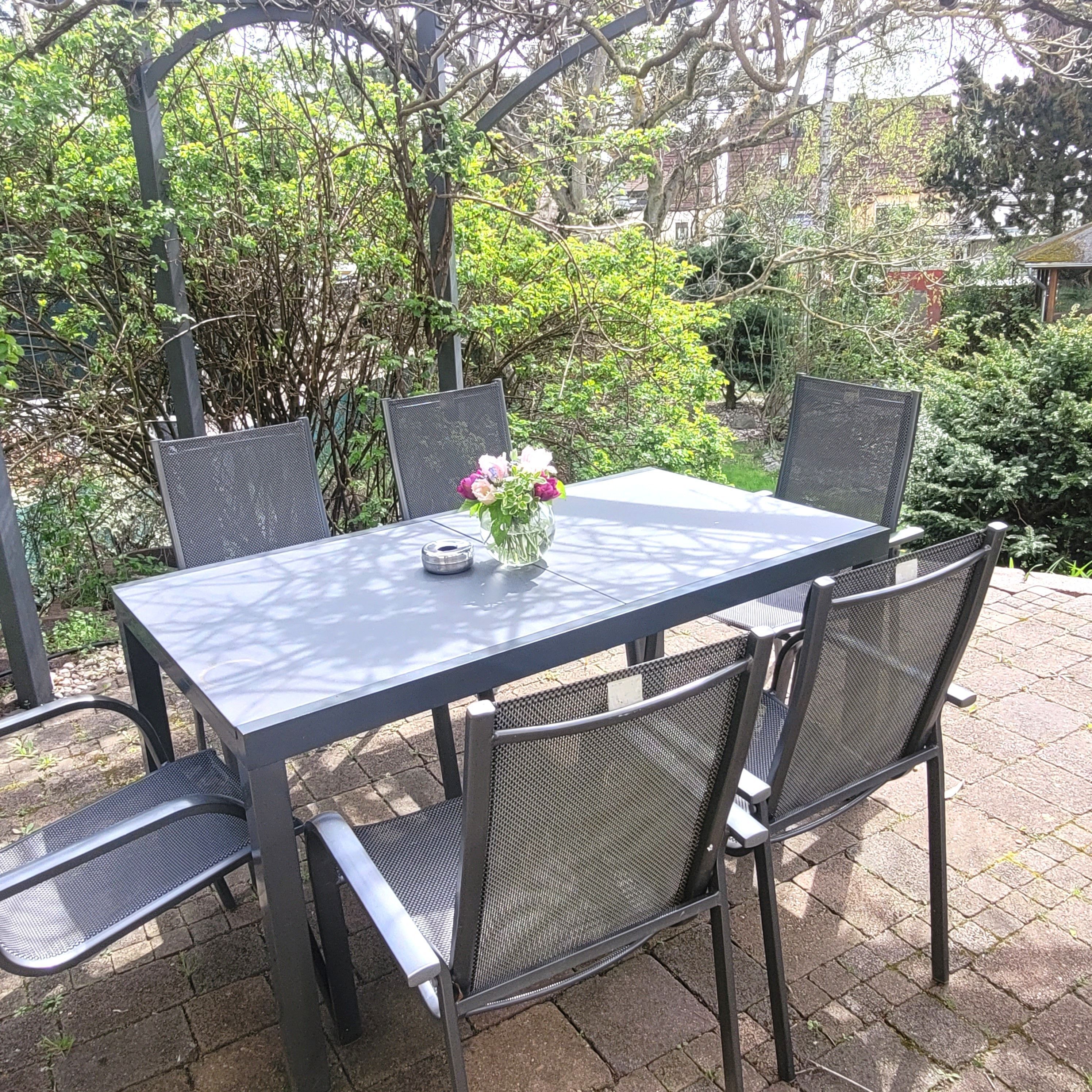 An outdoor patio with a rectangular table and four chairs.