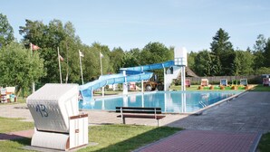 Ein Pool mit blauer Rutsche, einem Picknicktisch und einem überdachten Grillbereich.