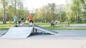 Ein Skatepark mit einer Rampe und mehreren Kindern sowie Erwachsenen, die sich dort tummeln.