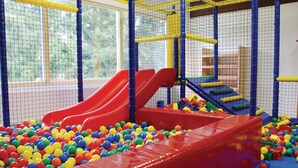 Ein Spielbereich mit zwei roten Rutschen und einem Ballbecken voller bunter Bälle.