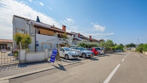 A parking area with several cars, a building with a signboard, and a clear sky. - Amazing apartment in Porec with WiFi (Porec)
