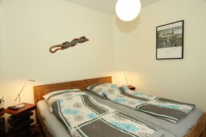 Un dormitorio con dos camas individuales, cabeceros de madera, lámparas de noche, un adorno en la pared y un cuadro enmarcado.