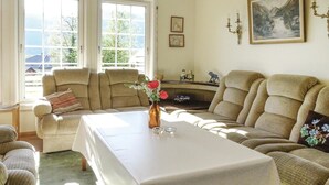 Een gezellige woonkamer met een zithoek, een eettafel en een open haard.