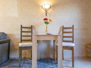 Ein kleiner Holztisch mit zwei Stühlen, einer Blumenvase und einer Wandleuchte.