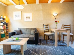 A cozy living room with a sofa, two chairs, a table, and a bookshelf.