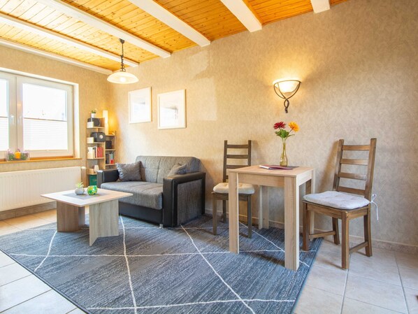 A cozy living room with a sofa, a small table, a chair, and a bookshelf.