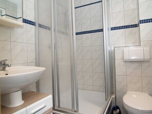 A bathroom with a glass-enclosed shower, a white sink, and a toilet.