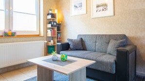 En hyggelig stue med en grå sofa, et træbord og en reol med forskellige ting.