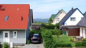 Ein Wohngebiet mit Häusern, einem Auto auf der Auffahrt und Blick auf das Meer im Hintergrund.
