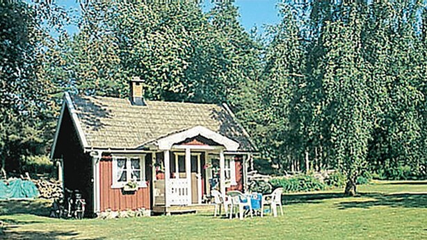 Een klein huis met een veranda en een gazon.