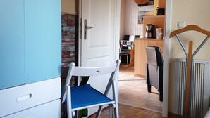 Una cucina compatta con macchina da caffè, un'area pranzo con una sedia e un termosifone.