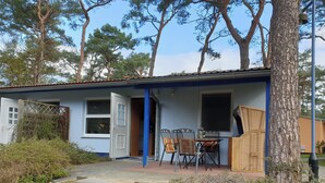 Un edificio con facciata blu, una porta aperta su un ambiente, un tavolo con sedie e una finestra.
