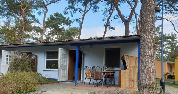 A building with a blue exterior, a door open to a room, a table with chairs, and a window.