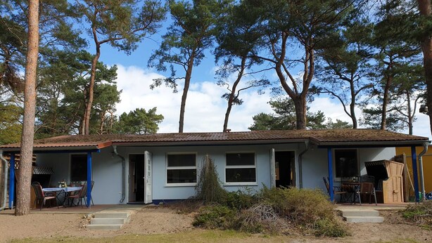 Una casa a un piano con facciata blu, un portico e un piccolo giardino.