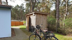 Una rimessa in legno con una bicicletta parcheggiata davanti.