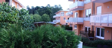 A multi-story residential building with balconies, surrounded by greenery.