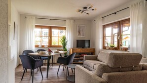 Una sala moderna con sofá, mesa de comedor, sillas y televisor.