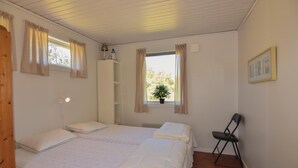 A bedroom with two beds, a chair, a window with curtains, a potted plant, and a framed picture on the wall. - Awesome home in Hunnebostrand (Hunnebostrand)