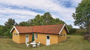 A small wooden cabin with a red-tiled roof, a small porch, and a table with chairs. - Awesome home in Hunnebostrand (Hunnebostrand)