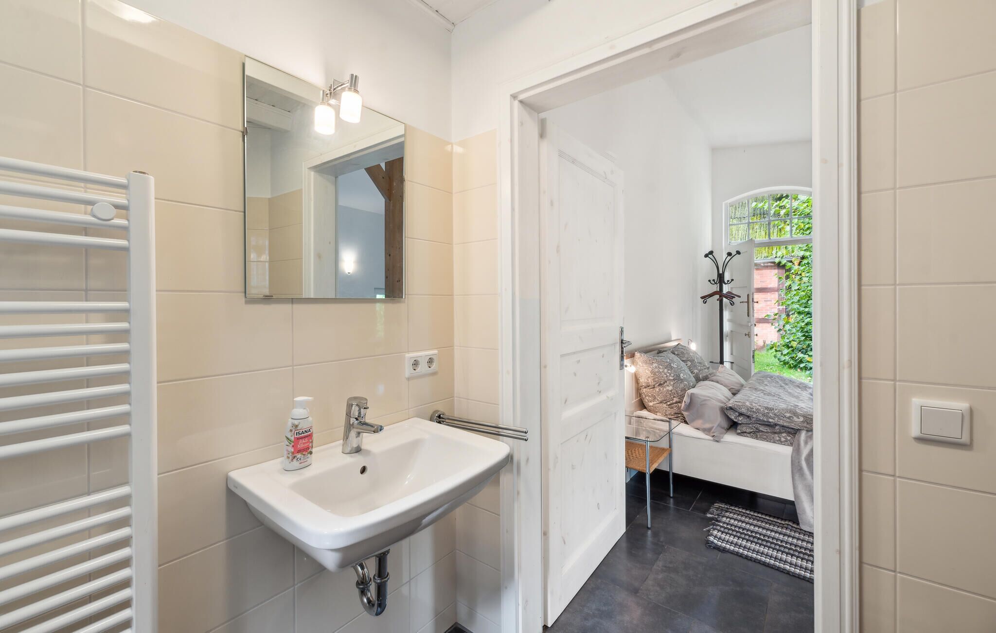 A bathroom with a white sink, mirror, and towel rack.