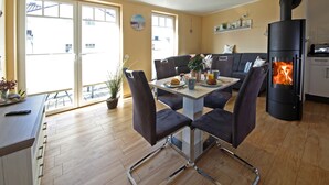 Een moderne keuken met een centraal eiland, een eethoek met stoelen, een bank en een open haard.