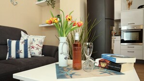 Een woonkamer met een bank, een salontafel met een vaas, een fles, een glas en boeken.