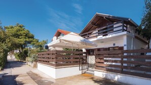 Una casa de dos pisos con un balcón, una valla de madera y un cielo azul despejado.