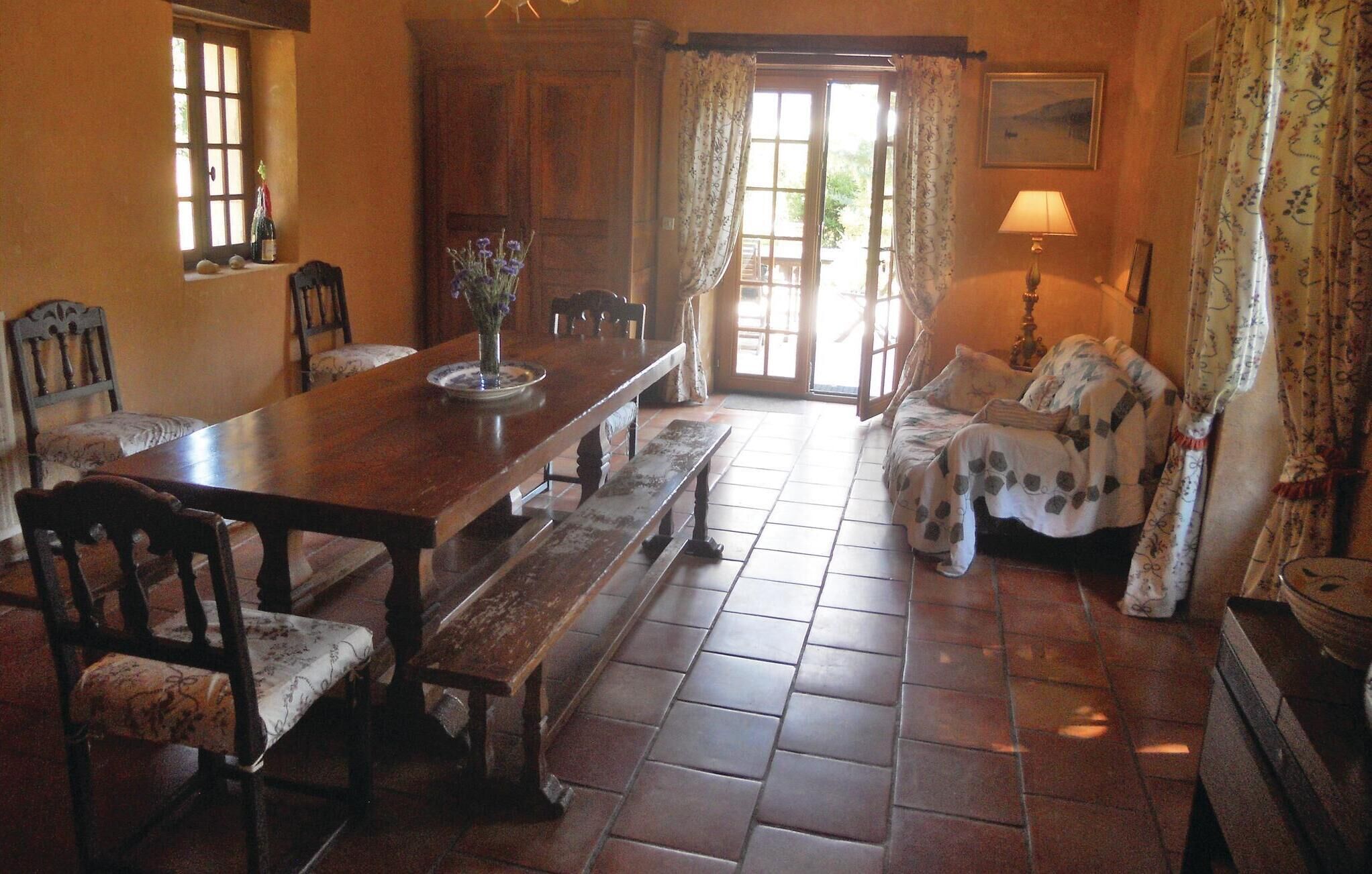 A dining room with a wooden table, benches, chairs, and a floral vase.