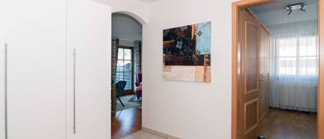 A hallway with a white door, a painting, and a wooden door leading to another room.