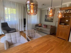 A living room with a wooden dining table, two sofas, and a television.