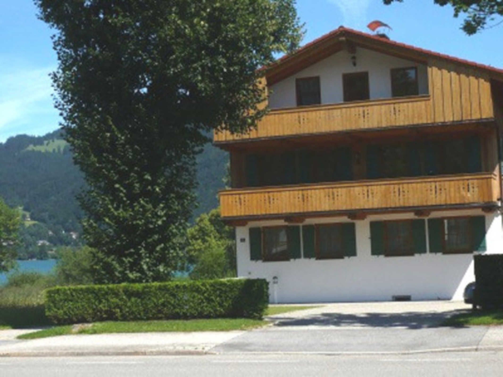 Un bâtiment à deux étages doté d’un balcon, entouré de verdure et bordé par un lac.