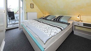 A bedroom with a bed, a desk, a chair, and a radiator.
