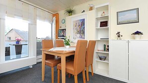 A dining area with a table and chairs, a television, and a bookshelf.