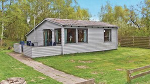 Eine kleine, einstöckige Hütte mit Veranda und überdachter Sitzgelegenheit im Freien.