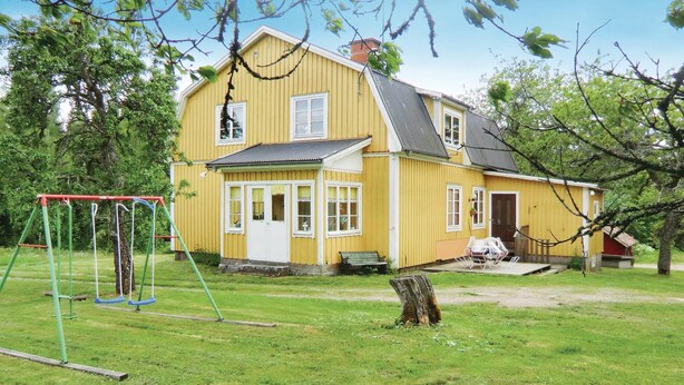 A yellow house with a porch, a swing set, and a bench. - 2 bedroom lovely home in Järnforsen (Järnforsen)