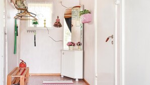 A hallway with a white door, a mirror, a pink plant, and a fire extinguisher. - 2 bedroom lovely home in Järnforsen (Järnforsen)