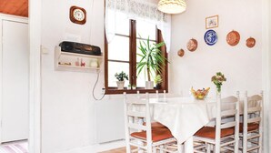 A dining area with a white table and chairs, a clock on the wall, and various decorative items. - 2 bedroom lovely home in Järnforsen (Järnforsen)