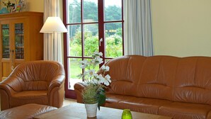 A room with a brown leather sofa, a wooden cabinet, and a window with curtains. - FH Lena to the beach only a few minutes walk ca.200 m quiet - FH Lena to the beach only (Glowe)