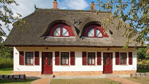 A traditional house with a thatched roof, red shutters, and numbered doors. - FH Lena to the beach only a few minutes walk ca.200 m quiet - FH Lena to the beach only (Glowe)