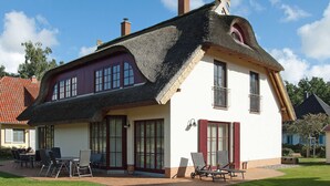A house with a thatched roof, large windows, and a patio with outdoor furniture. - FH Lena to the beach only a few minutes walk ca.200 m quiet - FH Lena to the beach only (Glowe)