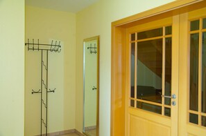 Una habitación con puerta de madera, perchero y espejo.