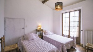 A bedroom with two single beds, a wooden chair, a small table with a lamp, and a window with blinds. - Cozy home in Draguignan (Draguignan)