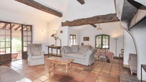 A spacious living area with a high ceiling, exposed wooden beams, and a tiled floor. There are two sofas, a coffee table, and a dining table with chairs. - Cozy home in Draguignan (Draguignan)