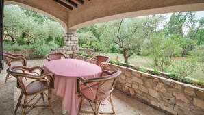 An outdoor patio with a round table and wicker chairs, surrounded by a stone wall and lush greenery. - Cozy home in Draguignan (Draguignan)