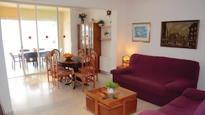 A living room with a purple sofa, a wooden coffee table, and a dining area with a glass table and chairs.
