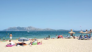A beach with people sunbathing, swimming, and playing.