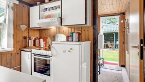Eine kleine Küche mit Holzwänden, einem eingebauten Backofen und einem Kühlschrank.