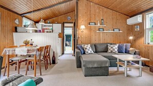 Ein gemütliches Blockhaussinnere mit Essbereich, einer Couch und einem kleinen Tisch.