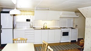 Una cucina compatta con mobili bianchi, un fornello, un lavandino e un'area pranzo con tavolo e sedie.
