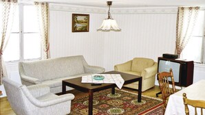 Un soggiorno con divano, poltrone, tavolino, televisore e un tappeto decorato.